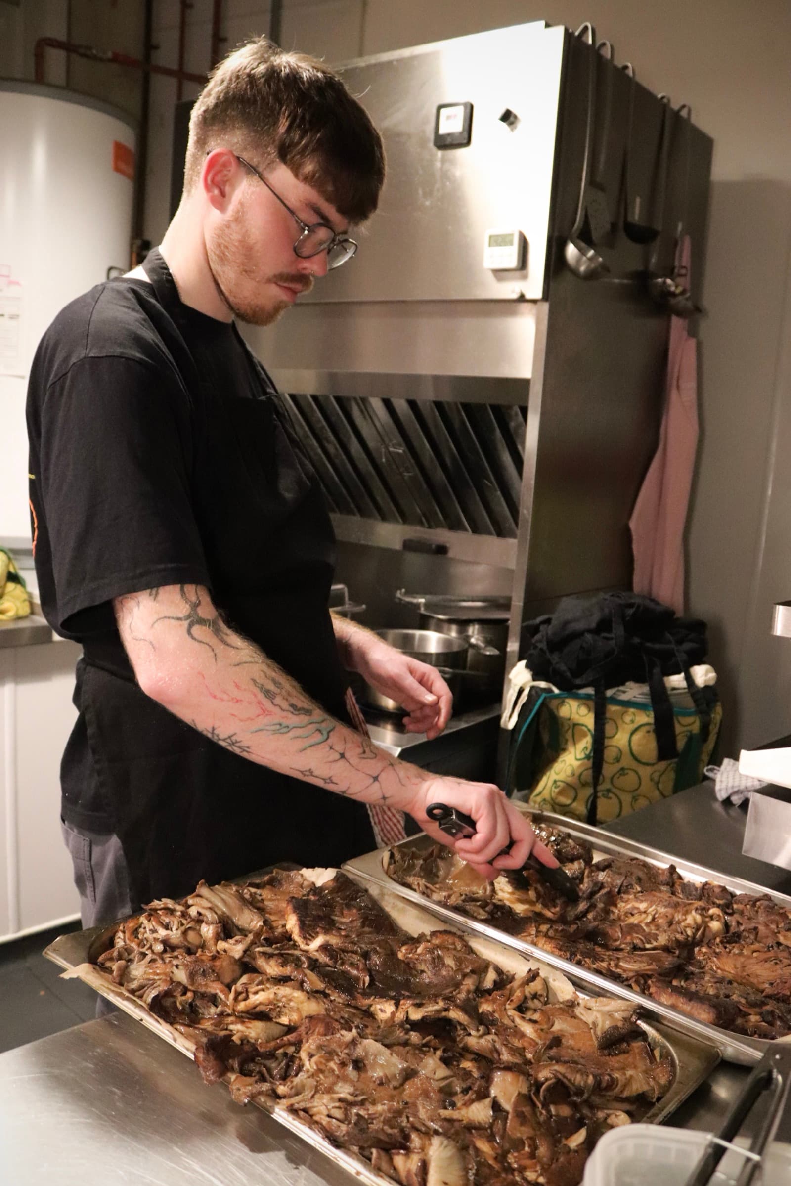 A cook seasoning trays of roasted mushrooms