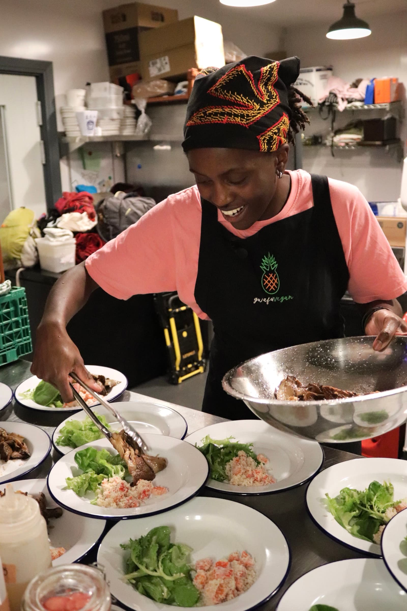 A cook plating salads in the kitchen, smiling