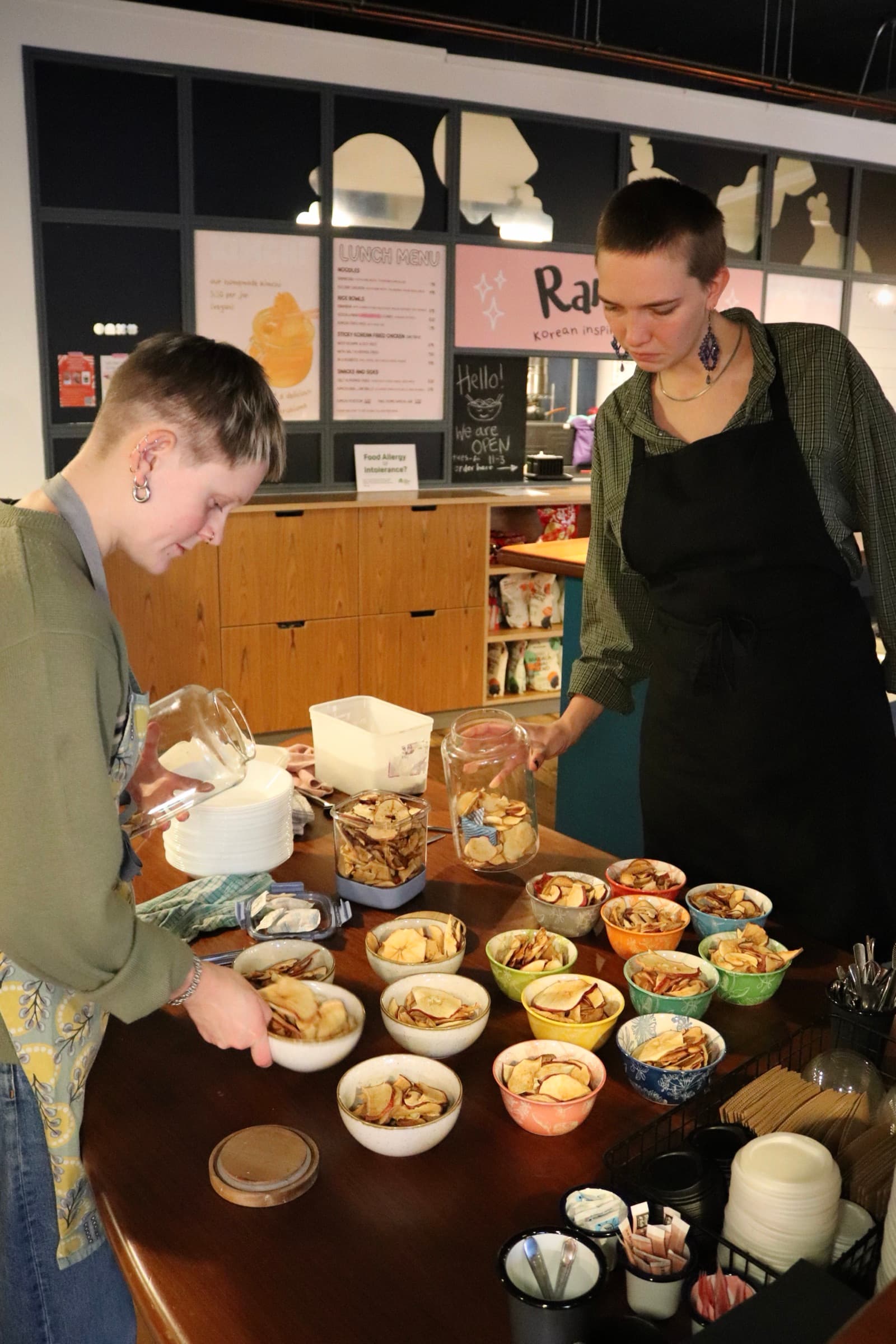 Volunteers filling small bowls with dried apple slices