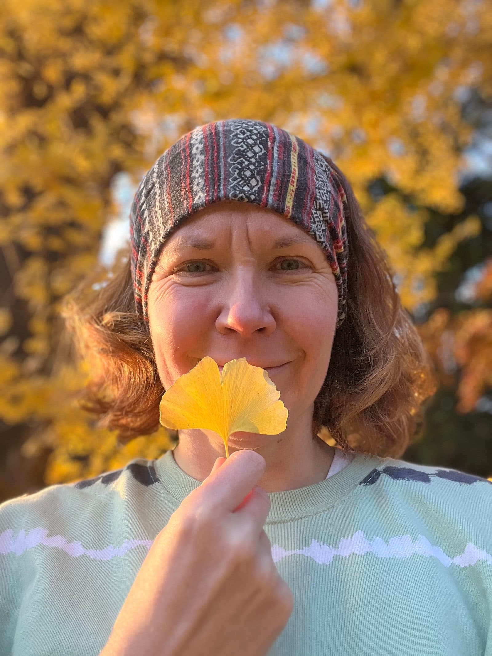 Aga holding a yellow gingko biloba leaf in front of her face